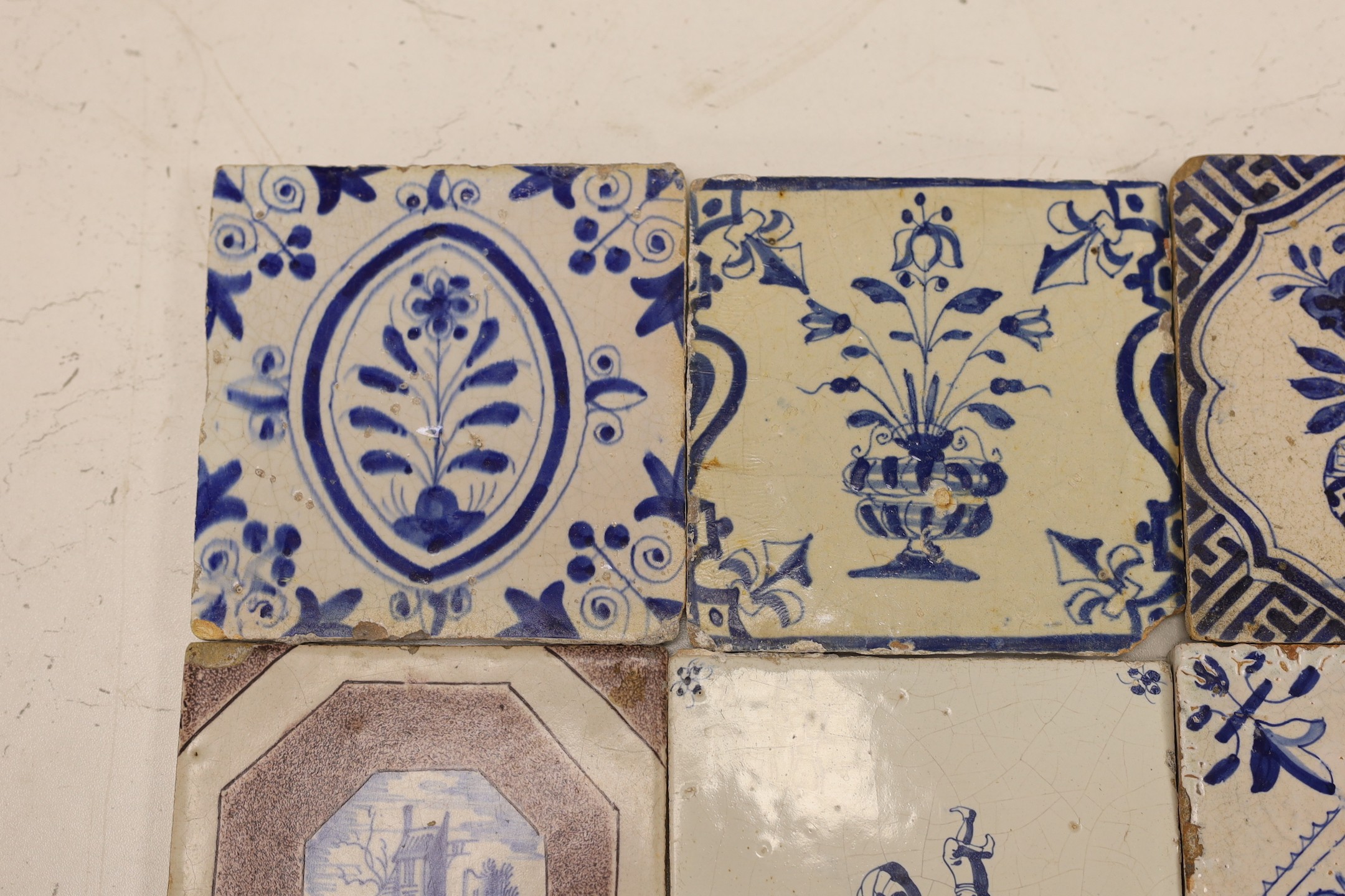 Four mid 17th century Delft blue and white ‘urn of flowers’ tiles, and an 18th century Delft ‘acrobats’ tile and blue and manganese ‘landscape’ tile (6)